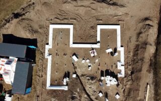 Dronefoto fra byggeri på blødjord i Klitmøller. Hvide funderingsblokke lyser op på den brune jord.