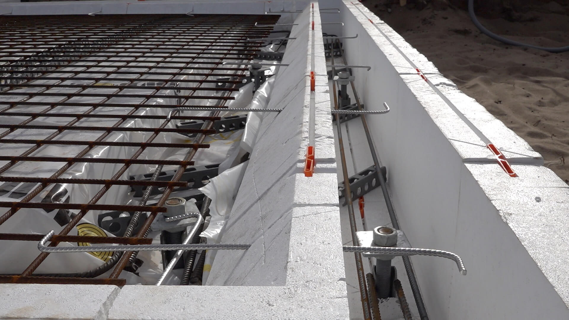 Foto på tværs af Sundolitt F-sokler med armeringsjern og toppen af stålskruer i klar til støbning af fundament og terrændæk